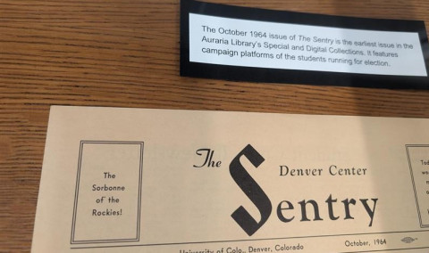 Vintage October 1964 issue of *The Sentry*, a University of Colorado Denver student newspaper, lies on a wooden table; a placard describes its historic origin.