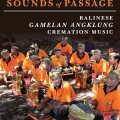 Group of Balinese musicians in orange shirts and traditional headwear play Gamelan Angklung instruments in a shaded outdoor setting, conveying cultural vibrancy.