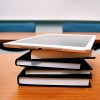 an electronic tablet on top of books